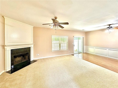 Unfurnished living room featuring a ceiling fan, carpet, and a tile fireplace