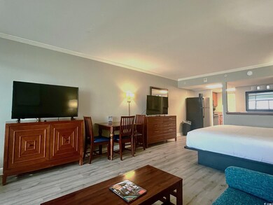 Bedroom with ornamental molding, light hardwood / wood-style flooring, stainless steel fridge, and ensuite bath