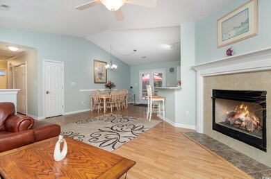 Living area with visible vents, wood finished floors, ceiling fan with notable chandelier, a tile fireplace, and lofted ceiling