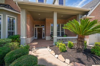 The freshly mulched flowerbeds with flagstone borders, knock-out roses, nandenas, and a sago palm tree line the walkway to this quaint, covered front porch with recessed lighting and ample space to accommodate a bench or seating arrangement.