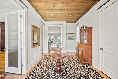Entryway with wood ceiling, crown molding, and wood finished floors