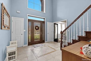Foyer entrance with inlaid floor details, a high ceiling, stairs, and light tile patterned floors
