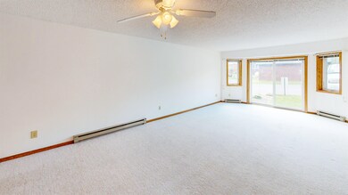 Carpeted empty room featuring a baseboard heating unit, a textured ceiling, and ceiling fan