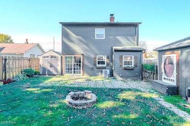 Back of property with a storage unit, a fire pit, a patio, a fenced backyard, and a chimney