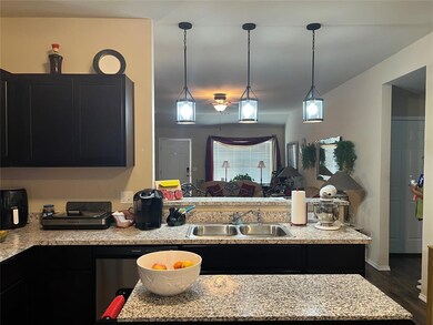 Kitchen featuring pendant lighting, dark wood-style flooring, and dark cabinets