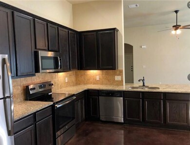 Kitchen featuring stainless steel appliances, concrete floors, tasteful backsplash, light stone countertops, and a ceiling fan