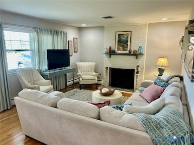 Living area featuring wood finished floors, a fireplace, recessed lighting, and a baseboard radiator