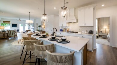 Kitchen with a sink, stainless steel gas cooktop, premium range hood, a ceiling fan, and a kitchen island with sink