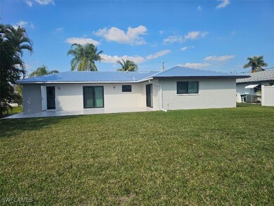 Rear view of house with stucco siding, a patio, a yard, and metal roof