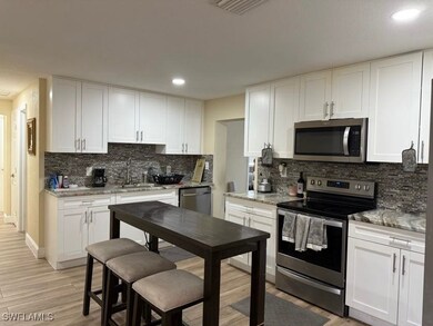 Kitchen featuring stainless steel appliances, light stone countertops, white cabinets, light wood-style floors, and recessed lighting