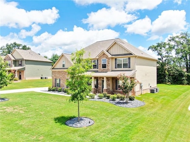 Craftsman-style house featuring board and batten siding, a front yard, covered porch, and brick siding