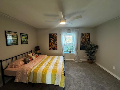 Carpeted bedroom featuring crown molding, baseboa