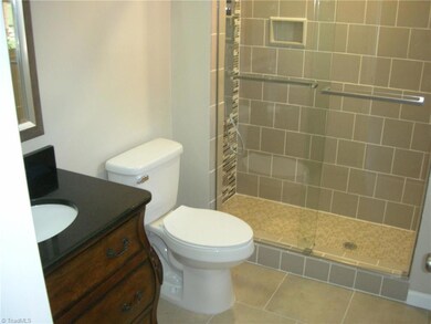 Primary Bathroom: Features include ceramic tile flooring for easy cleaning, a window for natural lighting, recessed lighting, fresh paint, a decorative vanity, new fixtures, and a low step entry ceramic and tile shower with a multi-function shower.