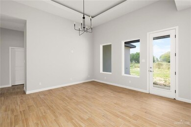 Spare room with a notable chandelier, light wood-style floors, and baseboards