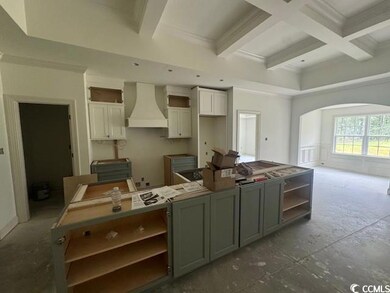 Kitchen featuring premium range hood, a center island, beam ceiling, arched walkways, and coffered ceiling