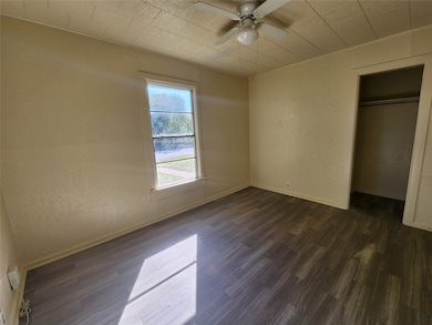 Unfurnished bedroom featuring dark hardwood / wood-style floors, a closet, and ceiling fan