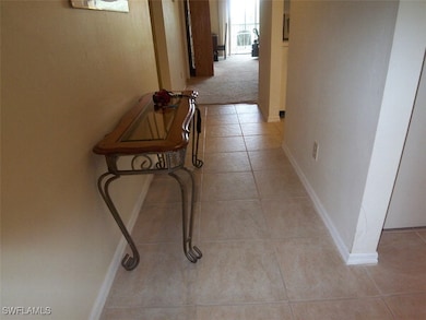 Hallway with light tile patterned floors, baseboar