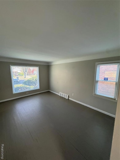 Spare room featuring baseboards and dark wood finished floors