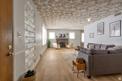 Living area featuring visible vents, a brick fireplace, wood finished floors, and a baseboard radiator