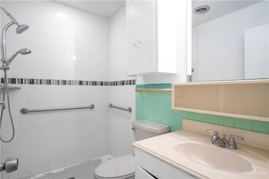 Bathroom with tiled shower, vanity, tile walls, and decorative backsplash