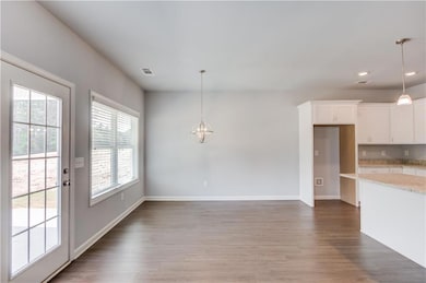 Unfurnished dining area featuring a chandelier, wood finished floors, baseboards, and recessed lighting