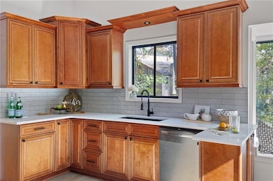 Kitchen with stainless steel dishwasher, decorative backsplash, and brown cabinetry