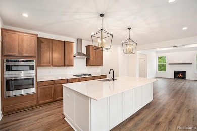 Kitchen with recessed lighting, appliances with stainless steel finishes, pendant lighting, white cabinets, and brown cabinets