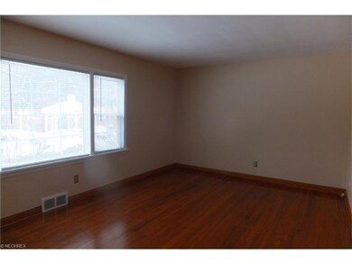 The spacious living room has wood floors, large pi