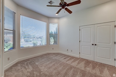 Unfurnished bedroom featuring light colored carpet, a closet, and ceiling fan