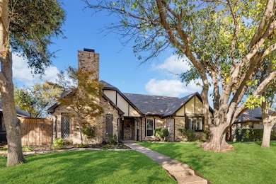 Tudor home featuring brick siding, a chimney, and stucco siding