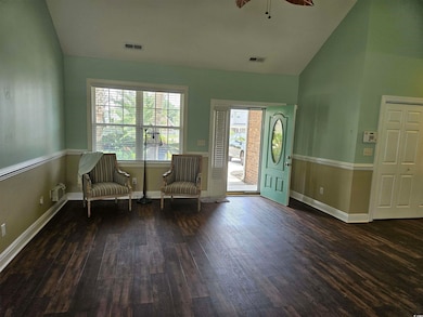 Living area featuring dark wood-style floors, high vaulted ceiling, and a ceiling fan
