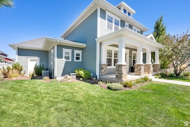 Rear view of house featuring a lawn, a porch, and stone siding