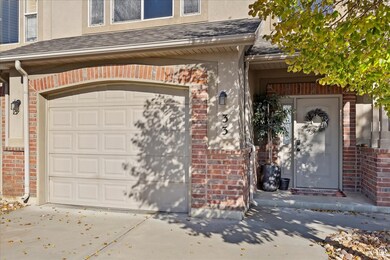 Property entrance featuring a shingled roof, brick siding, a garage, and stucco siding