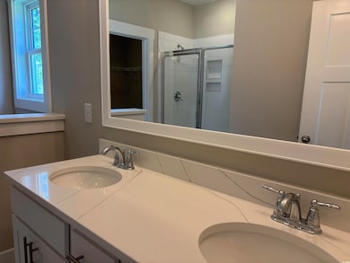 Bathroom with a shower stall, double vanity, and a spacious closet