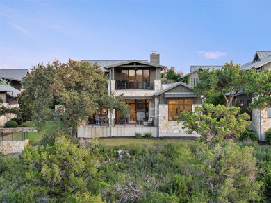 Back of property featuring a balcony, a chimney, stone siding, a patio, and a standing seam roof