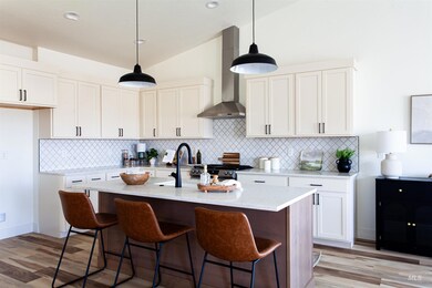 Kitchen with wall chimney exhaust hood, light wood-type flooring, vaulted ceiling, and decorative backsplash