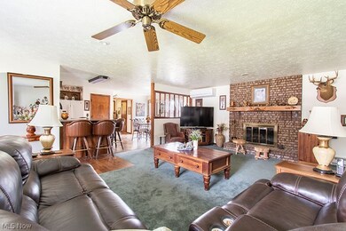 Carpeted living room with brick wall, a brick fireplace, ceiling fan, and a textured ceiling
