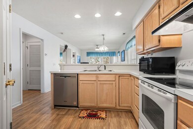 Kitchen featuring a peninsula, exhaust hood, light