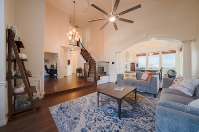 Living room with stairs, dark wood floors, a decorative wall, arched walkways, and a chandelier