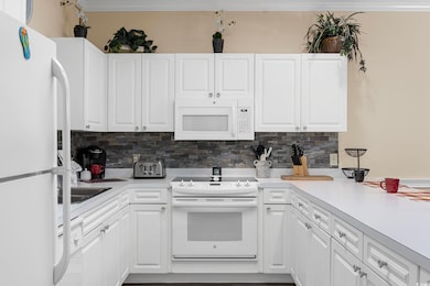 Kitchen with white appliances, tasteful backsplash