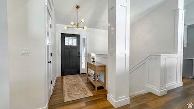 Foyer entrance featuring wood finished floors, a chandelier, and lofted ceiling