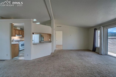 Unfurnished living room with light carpet, lofted ceiling, and a textured ceiling