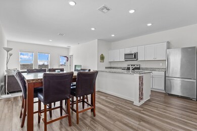 Kitchen featuring appliances with stainless steel finishes, white cabinetry, light wood finished floors, recessed lighting, and light stone countertops