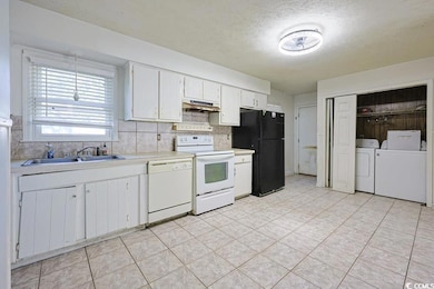 Kitchen with white cabinets, white appliances, light countertops, a textured ceiling, and separate washer and dryer