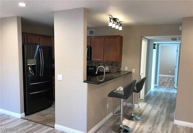 Kitchen featuring light wood-style floors, black appliances, a kitchen breakfast bar, decorative backsplash, and brown cabinets