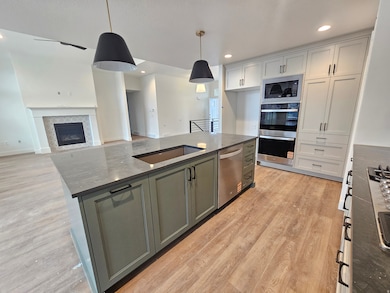 Kitchen featuring open floor plan, a center island, hanging light fixtures, light wood-style flooring, and recessed lighting