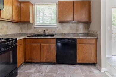 Kitchen with black appliances, a sink, baseboards,