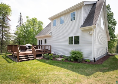 Back of property with a shingled roof, a lawn, and a deck