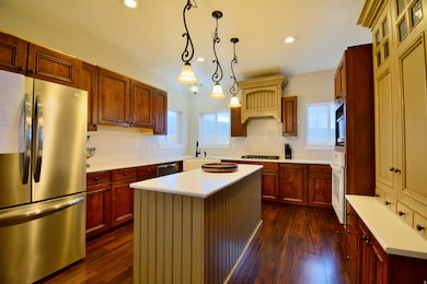 Kitchen with stainless steel appliances, a center island, light countertops, pendant lighting, and plenty of natural light
