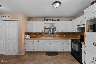 Kitchen featuring white cabinetry, black electric 